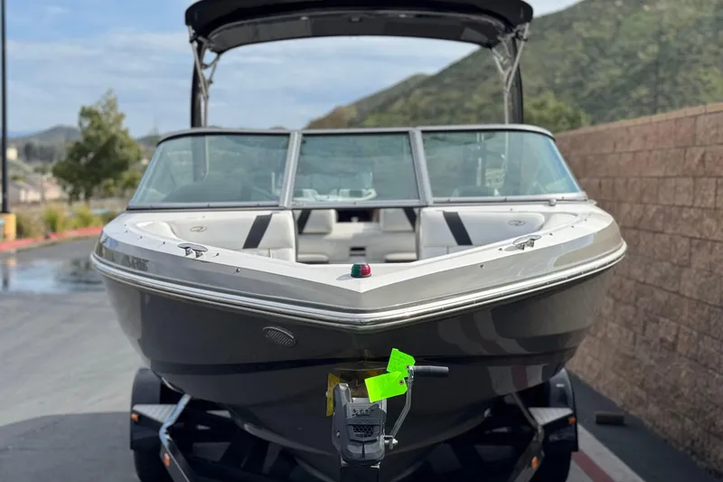 Slide: The Image of 2018 Regal 2100 Bowrider boat on trailer, parked outdoors with scenic background. - 2