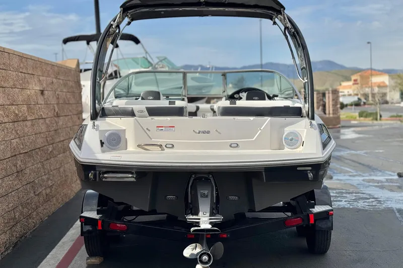 Slide: The Image of 2018 Regal 2100 Bowrider boat on trailer, parked outdoors. - 4