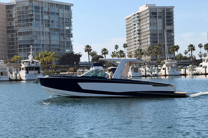 Slide: The Image of 2022 Aviara AV32 I/O boat cruising in a marina with modern buildings in the background. - 1