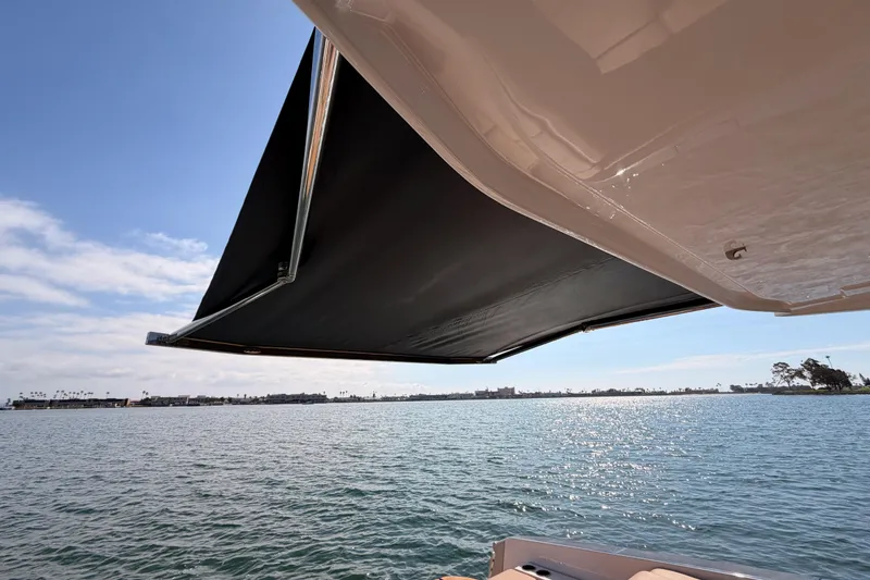 Slide: The Image of 2022 Aviara AV32 I/O boat with extended sunshade over calm waters. - 32