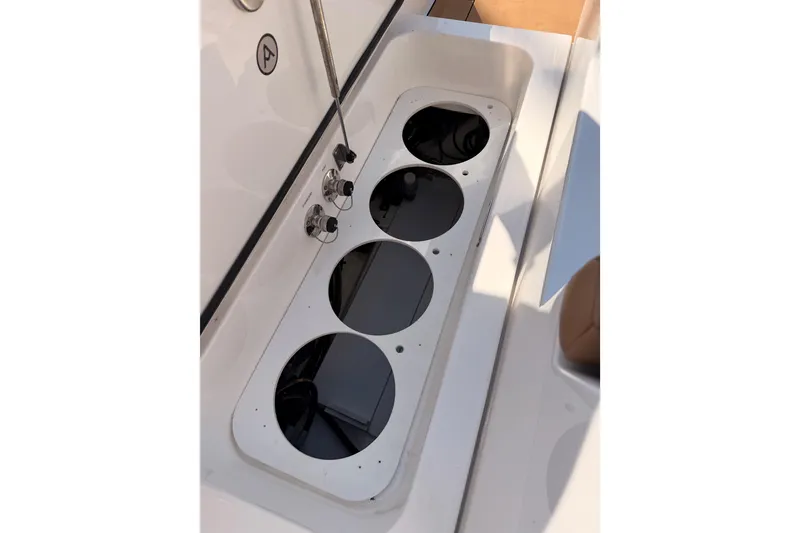 Slide: The Image of Aviara AV32 I/O 2022 boat storage compartment with cup holders and control knobs. - 48