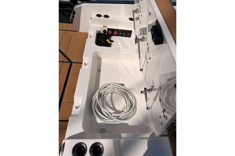 Slide: The Image of 2022 Aviara AV32 I/O boat storage compartment with coiled cables and control panel. - 51