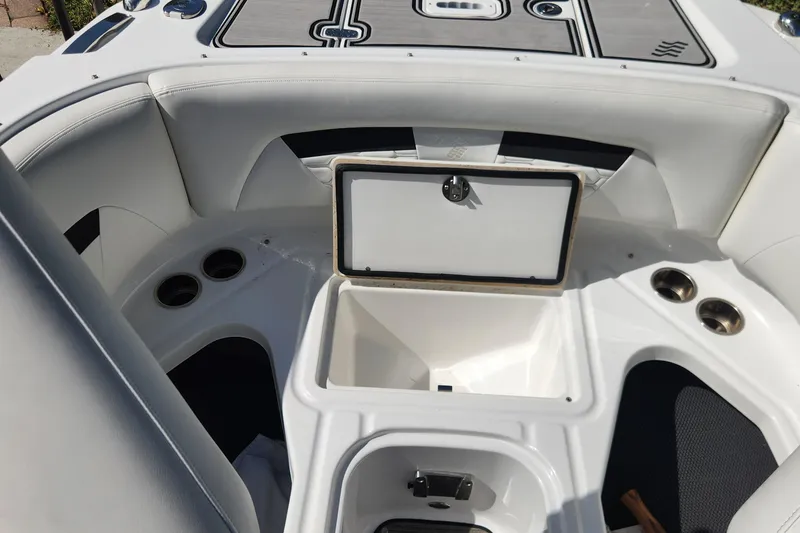 Slide: The Image of 2023 Four Winns HD8 OB boat interior with open storage compartment and cup holders. - 13