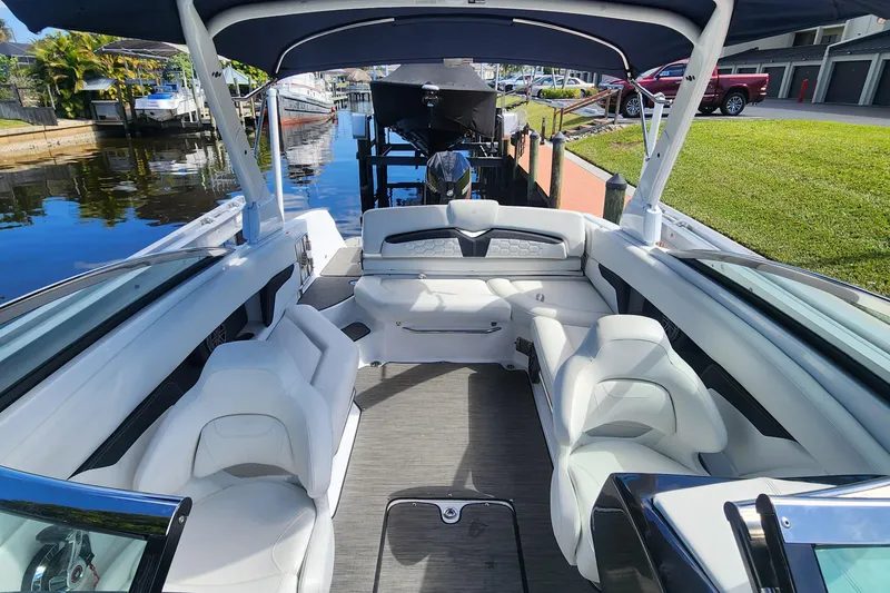 Slide: The Image of 2023 Four Winns HD8 OB boat interior with white seating and canopy, docked by a canal. - 43