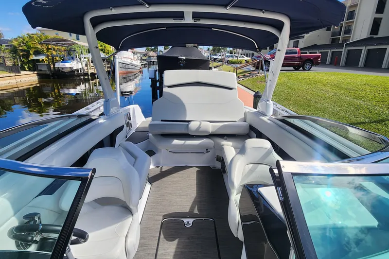 Slide: The Image of 2023 Four Winns HD8 OB boat interior with white seating and canopy, docked by a canal. - 58