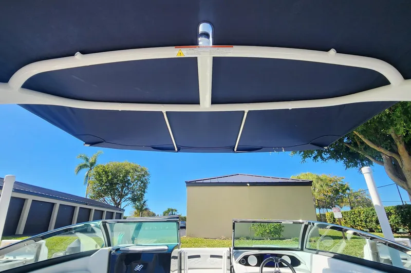 Slide: The Image of 2023 Four Winns HD8 OB boat with canopy, clear sky, and surrounding greenery. - 65