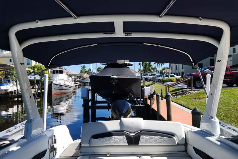 Slide: The Image of 2023 Four Winns HD8 OB boat docked, featuring a covered seating area and scenic marina view. - 7