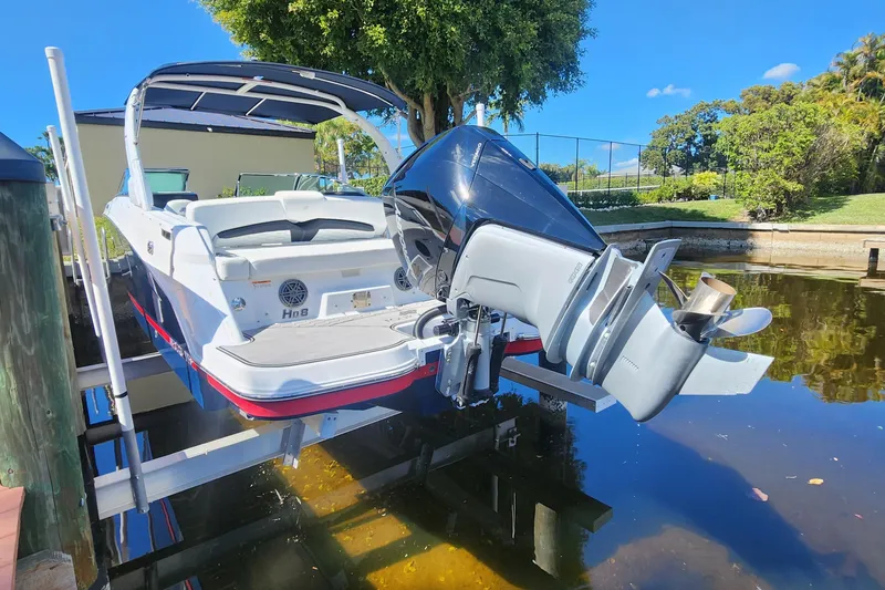 Slide: The Image of 2023 Four Winns HD8 OB boat on lift, showcasing outboard motor and sleek design. - 72