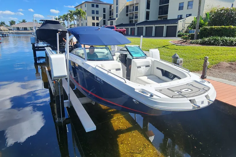 Slide: The Image of 2023 Four Winns HD8 OB boat docked by waterfront homes under a clear blue sky. - 79