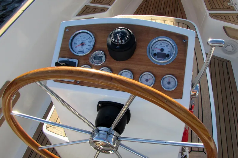 Slide: The Image of Steering wheel and dashboard of 2014 AdmiralsTender C28 boat, featuring gauges and compass. - 10