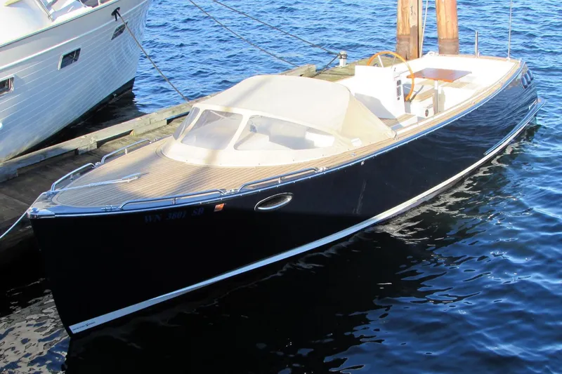 Slide: The Image of 2014 AdmiralsTender C28 boat docked on calm water, featuring sleek design and wooden deck. - 2