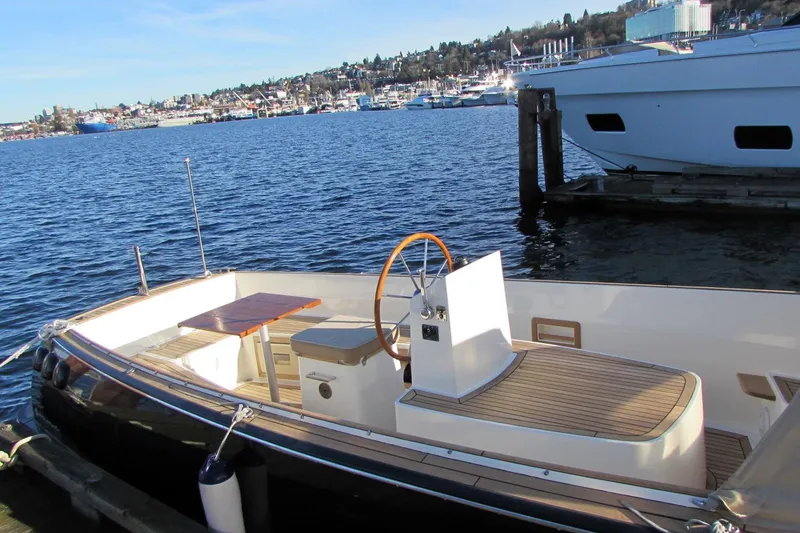 Slide: The Image of 2014 AdmiralsTender C28 boat docked by the waterfront, showcasing sleek design and wooden deck. - 4