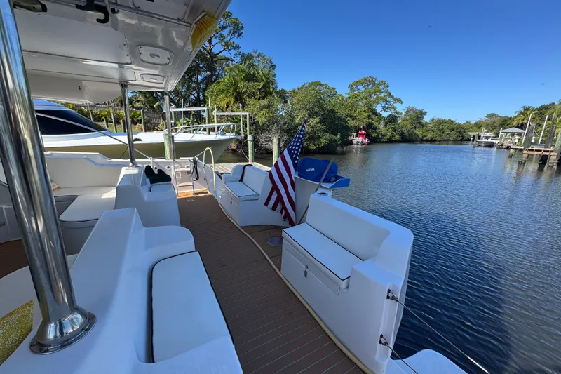 Slide: The Image of 2007 Africat Marine 420 yacht deck with seating, American flag, and scenic waterway view. - 95