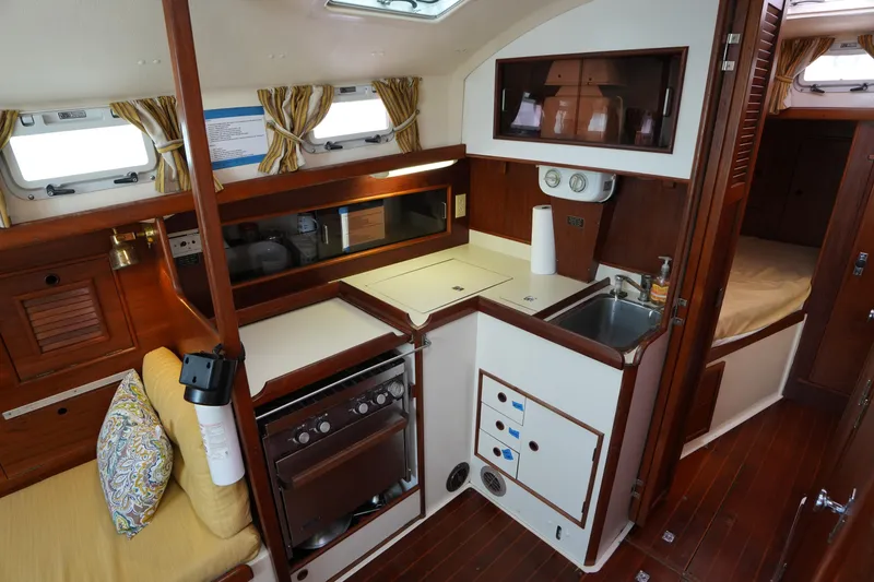 Slide: The Image of 1988 Nonsuch 30 Ultra yacht interior with kitchen, sink, and cozy seating area. - 16