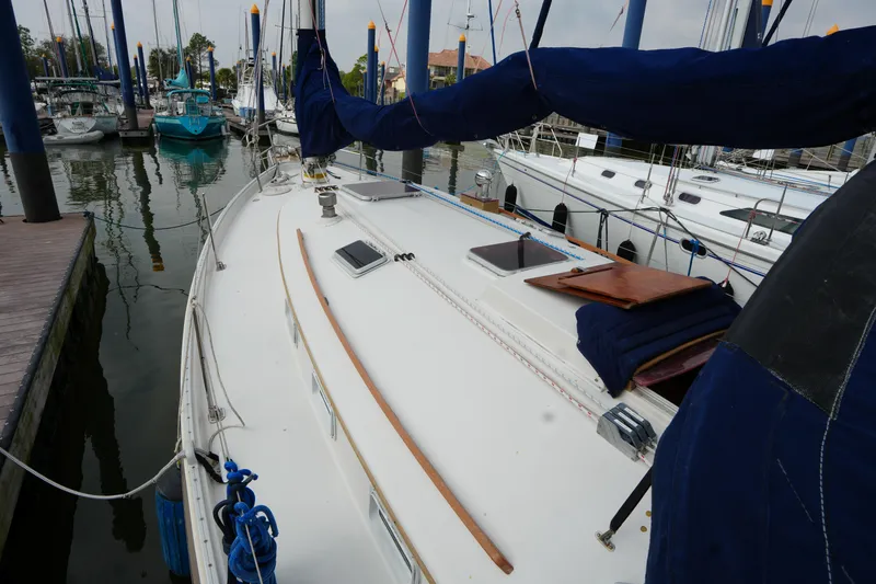 Slide: The Image of 1988 Nonsuch 30 Ultra sailboat docked in marina, featuring spacious deck and blue covers. - 7