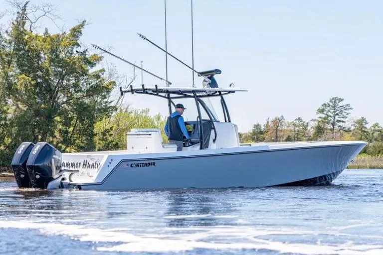 Slide: The Image of 2022 Contender 32 ST boat cruising on a calm lake with trees in the background. - 2