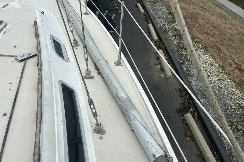 Slide: The Image of 1985 Catalina 36 sailboat deck with rigging and windows, docked near a paved path. - 11