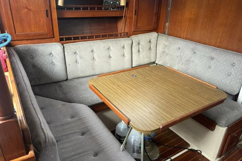 Slide: The Image of Cozy dining area in a 1985 Catalina 36 sailboat with wooden table and cushioned seating. - 24