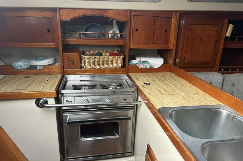Slide: The Image of 1985 Catalina 36 yacht kitchen with stove, wooden cabinets, and dual sink. - 31
