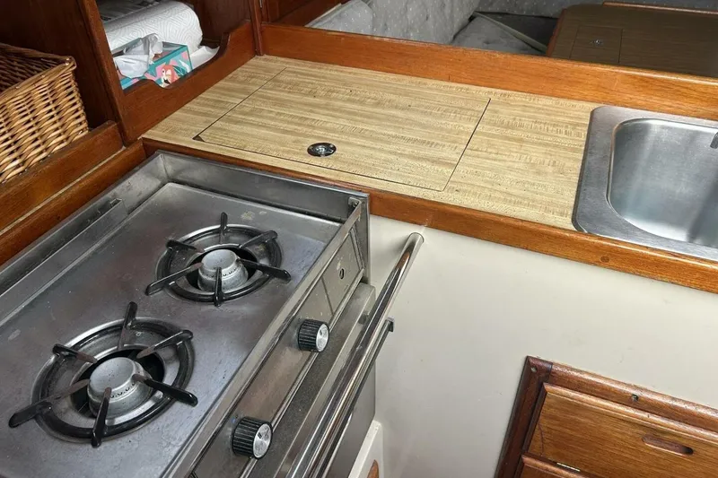 Slide: The Image of 1985 Catalina 36 yacht kitchen with stove, sink, and wooden cabinetry. - 33