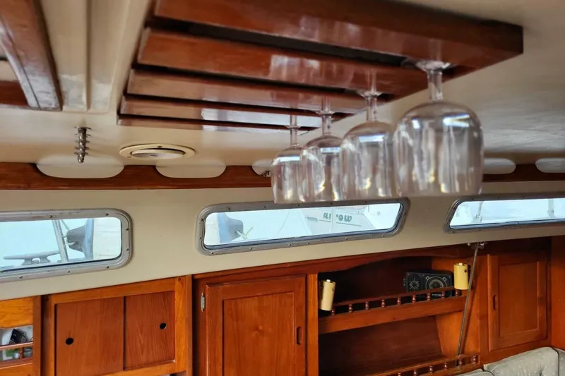 Slide: The Image of Interior of 1985 Catalina 36 sailboat with wooden cabinets and hanging wine glasses. - 35