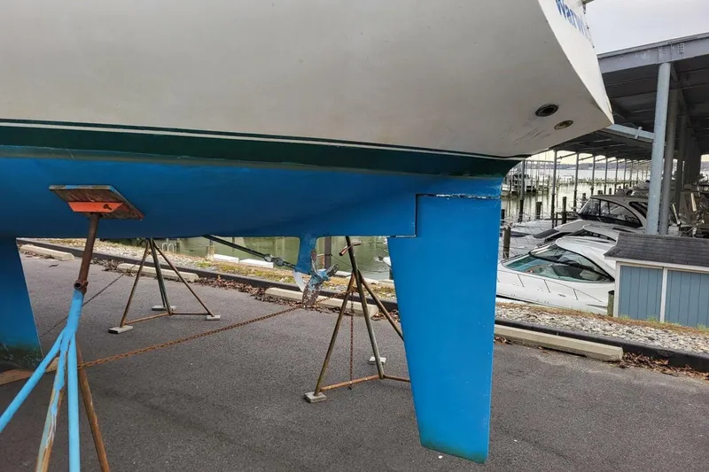 Slide: The Image of 1985 Catalina 36 sailboat on stands, showing blue hull and keel at marina. - 64