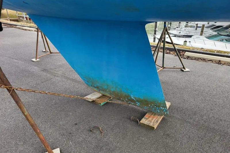 Slide: The Image of 1985 Catalina 36 sailboat keel on stands, showing blue paint and some wear. - 66
