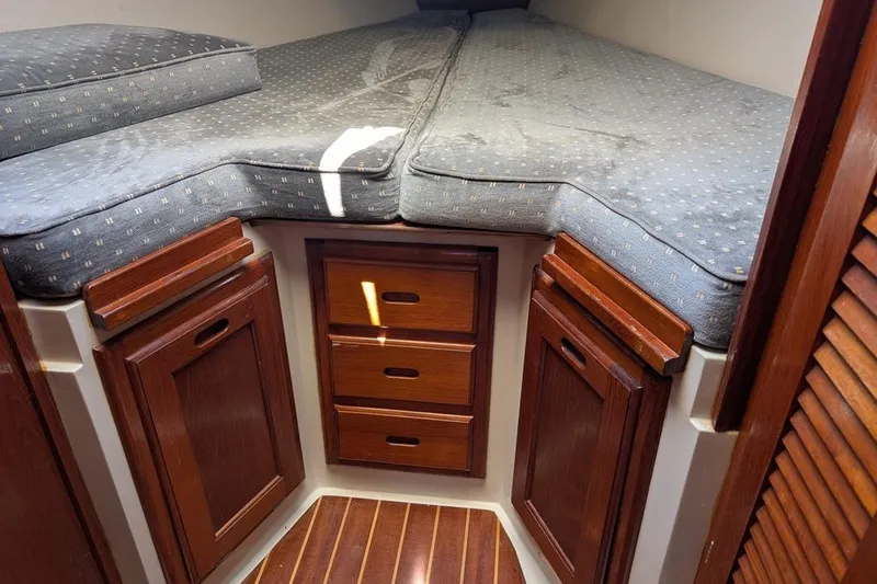 Slide: The Image of Interior cabin of a 1985 Catalina 36 sailboat with wooden cabinets and cushioned bedding. - 84