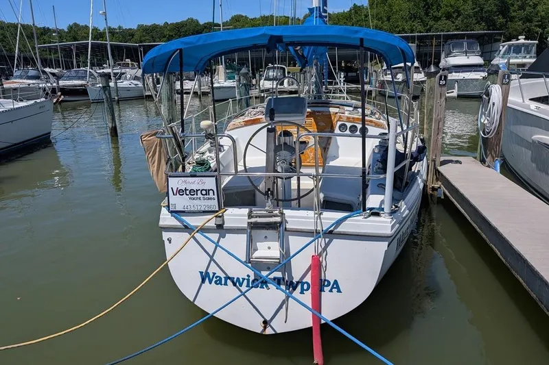 Slide: The Image of 1985 Catalina 36 sailboat docked at marina with blue canopy and sales sign. - 91