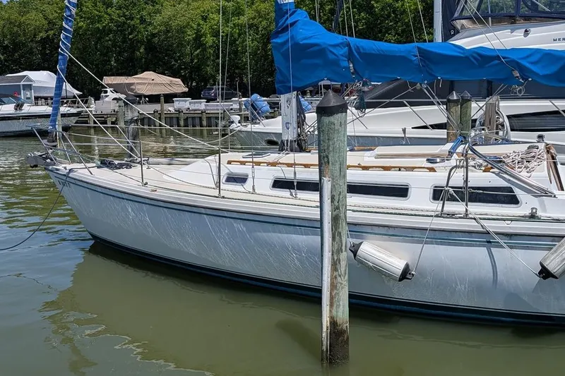 Slide: The Image of 1985 Catalina 36 sailboat docked in a marina, featuring blue sail covers. - 95