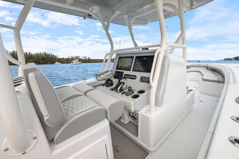 Slide: The Image of 2026 Yellowfin 32 Offshore boat interior with modern controls and seating on a sunny day. - 12