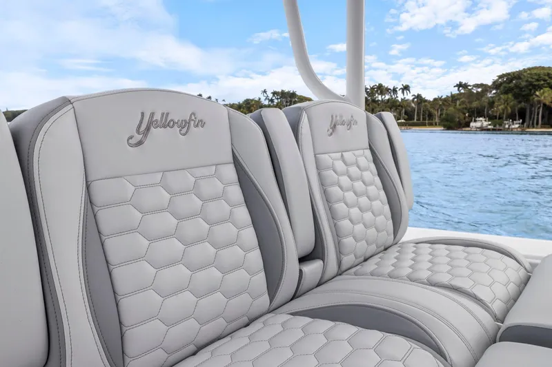 Slide: The Image of 2026 Yellowfin 32 Offshore boat seats with hexagonal pattern, overlooking serene water and lush greenery. - 19