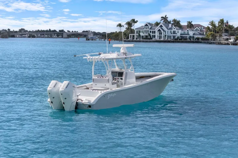 Slide: The Image of 2026 Yellowfin 32 Offshore boat on clear blue water near luxury waterfront homes. - 2