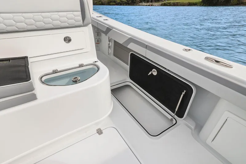 Slide: The Image of 2026 Yellowfin 32 Offshore boat interior with storage compartments and seating by the water. - 37