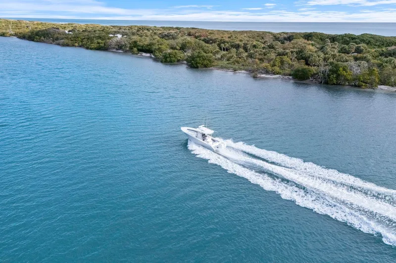 Slide: The Image of 2026 Yellowfin 32 Offshore boat cruising on blue water near a lush shoreline. - 52