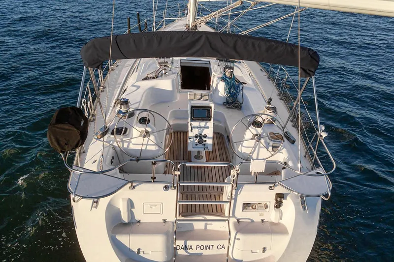 Slide: The Image of 1999 Catalina 470 sailboat on water, featuring dual steering wheels and spacious deck. - 22