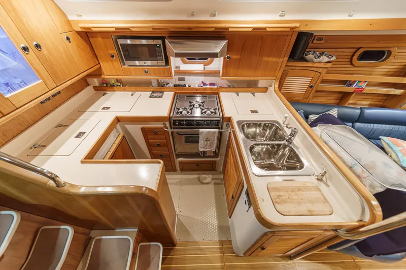 Slide: The Image of Interior of 1999 Catalina 470 yacht kitchen with wooden cabinetry and modern appliances. - 25