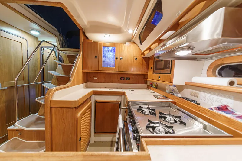 Slide: The Image of Interior of 1999 Catalina 470 yacht kitchen with wooden cabinetry and modern appliances. - 26