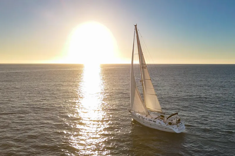 Slide: The Image of Sailing yacht Catalina 470 (1999) on ocean at sunset, reflecting sunlight. - 52
