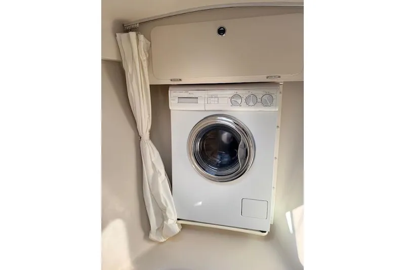 Slide: The Image of Washing machine inside a 1999 Catalina 470 yacht, with curtain and storage cabinet. - 53