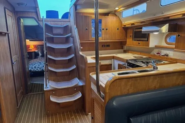 Slide: The Image of Interior of a 1999 Catalina 470 yacht featuring a wooden kitchen and cozy cabin area. - 60