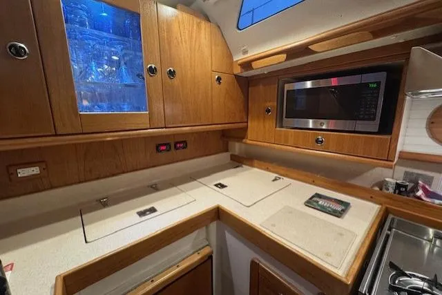 Slide: The Image of Wooden interior of a 1999 Catalina 470 yacht kitchen with microwave and cabinets. - 75