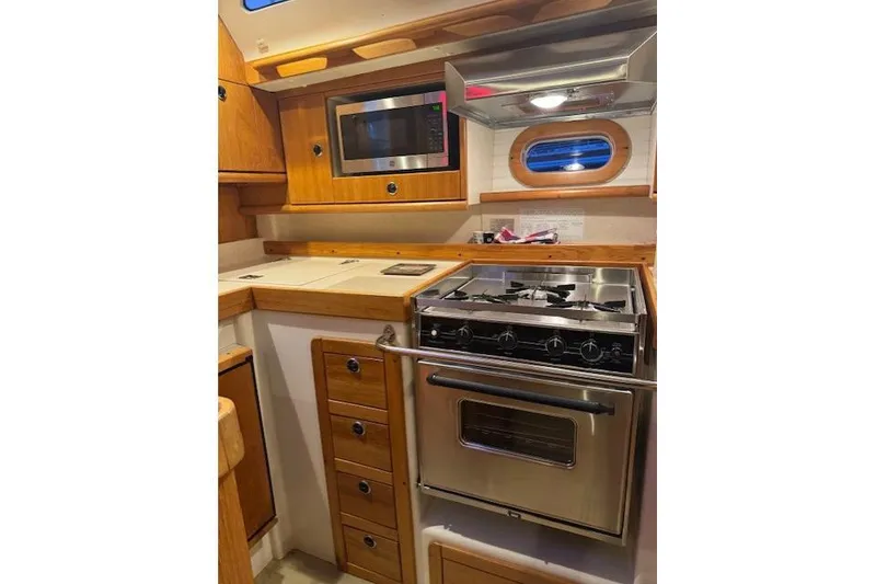 Slide: The Image of Galley kitchen in 1999 Catalina 470 yacht with stove, microwave, and wooden cabinetry. - 76