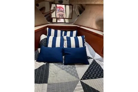 Slide: The Image of 1985 Ocean Yachts 38 Super Sport cabin with striped and solid pillows on a patterned bedspread. - 13