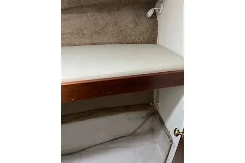 Slide: The Image of 1985 Ocean Yachts 38 Super Sport interior storage space with wooden shelf and carpeted wall. - 15