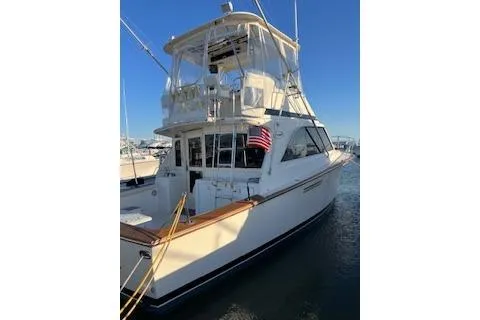 The Image of 1985 Ocean Yachts 38 Super Sport boat docked, featuring a classic design and American flag. - 0