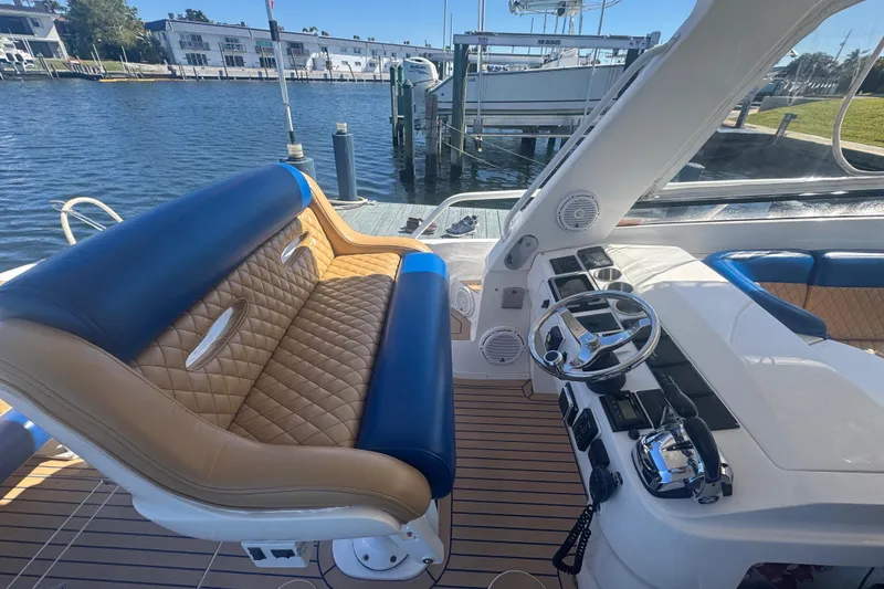 Slide: The Image of 2012 Intrepid 390 Sport Yacht cockpit with luxurious seating and modern controls, docked by the water. - 46
