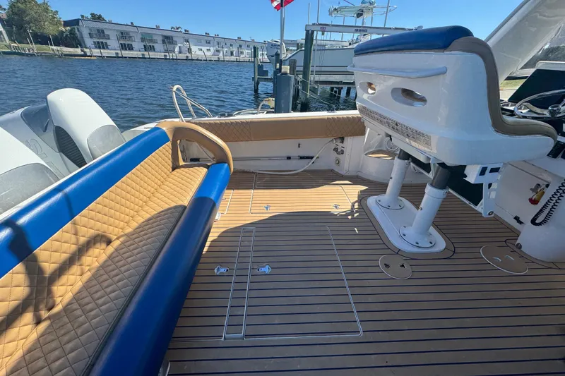 Slide: The Image of 2012 Intrepid 390 Sport Yacht interior with tan and blue seating, docked by the water. - 51