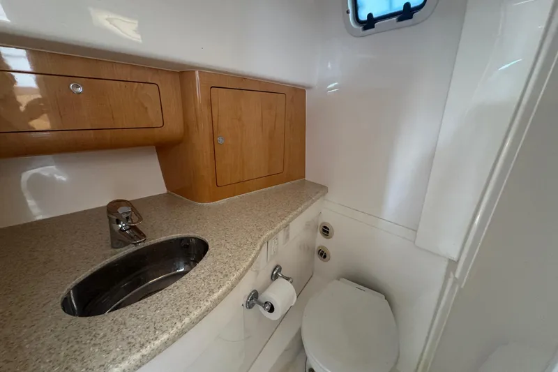 Slide: The Image of 2012 Intrepid 390 Sport Yacht bathroom with sink, toilet, and wooden cabinets. - 70