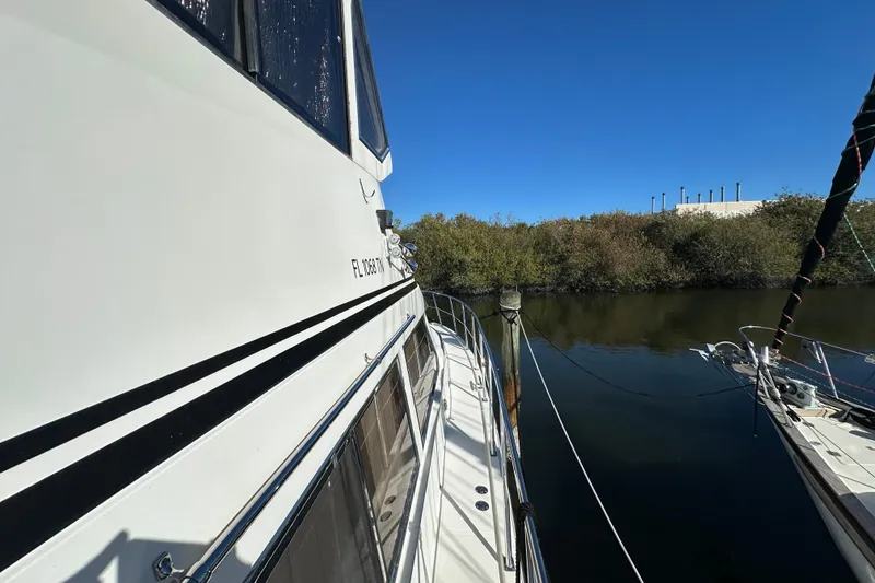 Slide: The Image of 2006 Novatec Islander 55 yacht docked by a calm river under clear blue skies. - 9